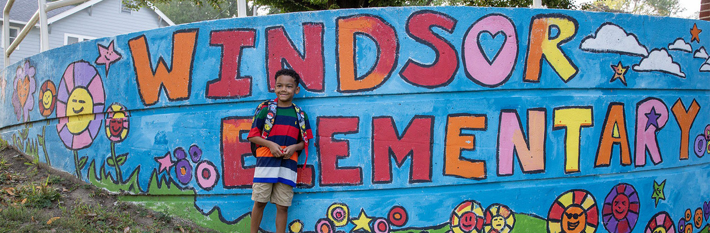 Student standing in front of Windsor mural 